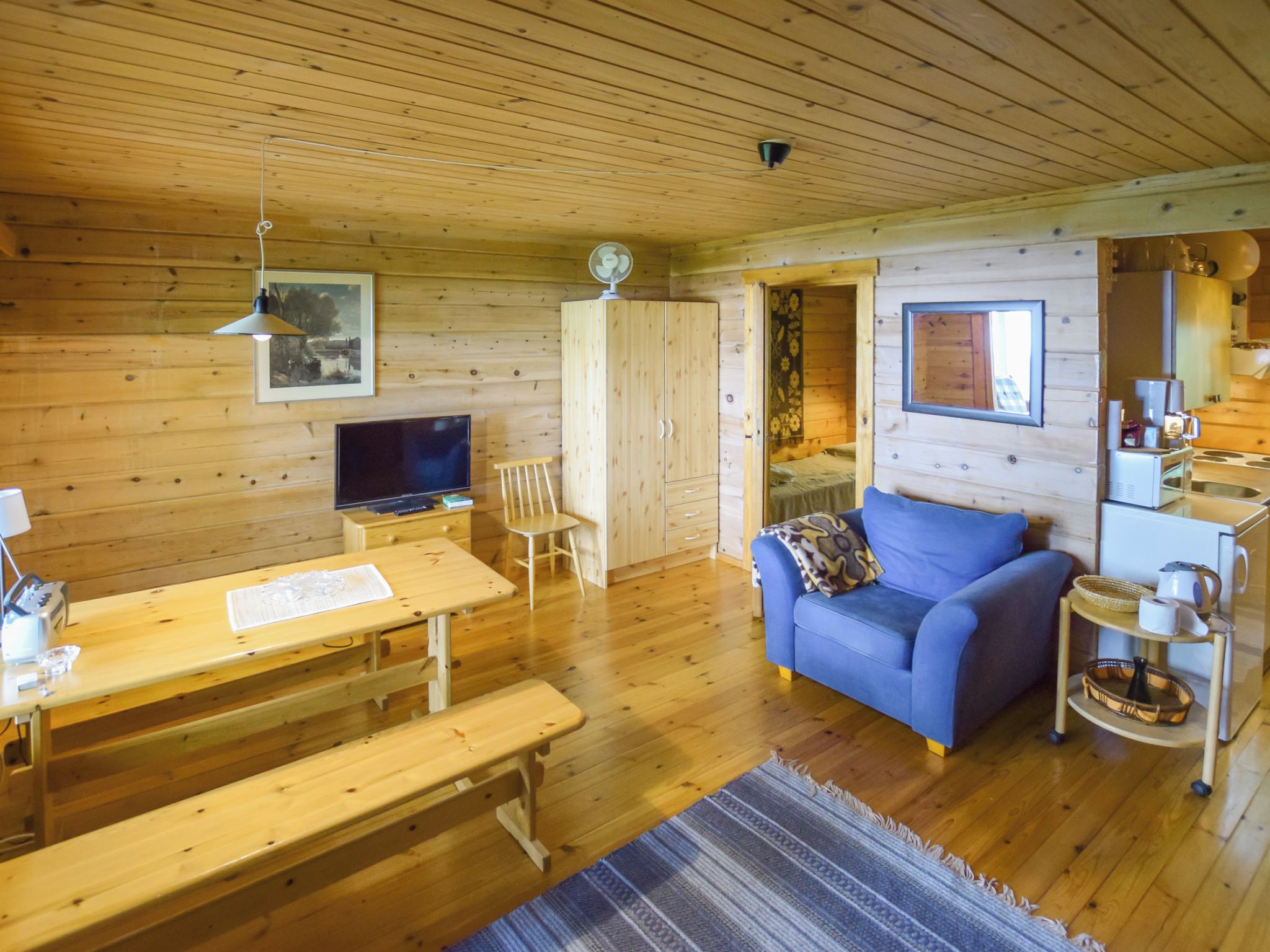 A wooden interior with a television, wooden furniture, a sofa, and a kitchenette.