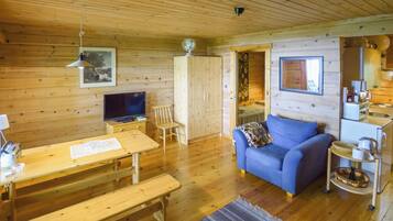A wooden interior with a television, wooden furniture, a sofa, and a kitchenette.