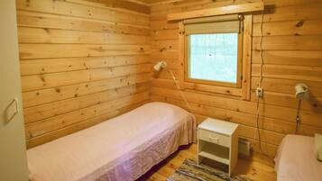 A small, wooden cabin room with a single bed, a nightstand, a window, and a power outlet.