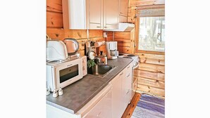 Una cocina compacta con armarios blancos, microondas, cafetera y lavamanos.