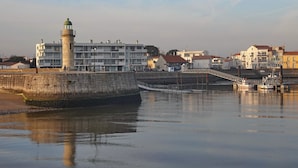 Una zona ribereña con un faro, un puente y edificios residenciales.