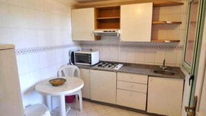A compact kitchen with white cabinets, a microwave, a gas stove, and a small dining table with chairs. - Residence Atlas Marrakech 3542 (Marrakech)