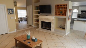 Una sala de estar con chimenea, televisor y mesa de centro.