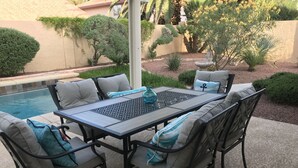 Un patio exterior con piscina, rodeado por un jardín con diversas plantas y un muro de piedra.