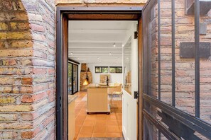 Un interior moderno con pared de ladrillo, puerta de madera y suelo de baldosas.