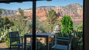 A room with a large window overlooking a canyon with red rock formations and greenery.