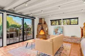 Una sala de estar moderna con chimenea, ventanas amplias y vistas al exterior.