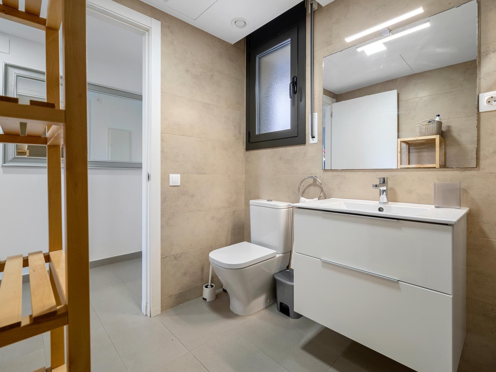 Un baño moderno con inodoro, lavamanos y espejo.