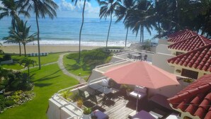 A balcony with outdoor seating, a view of the beach, and palm trees. - Cabarete Beach Front Houses A8.  TOP LOCATION IN CABARETE (Cabarete)