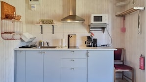 Een keuken met een centraal eiland, een magnetron, een koffiezetapparaat en een rode stoel.