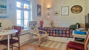 Een gezellige kamer met een houten vloer, een bed met een kleurrijk quilt, een stoel, een tafel en een raam met gordijnen.