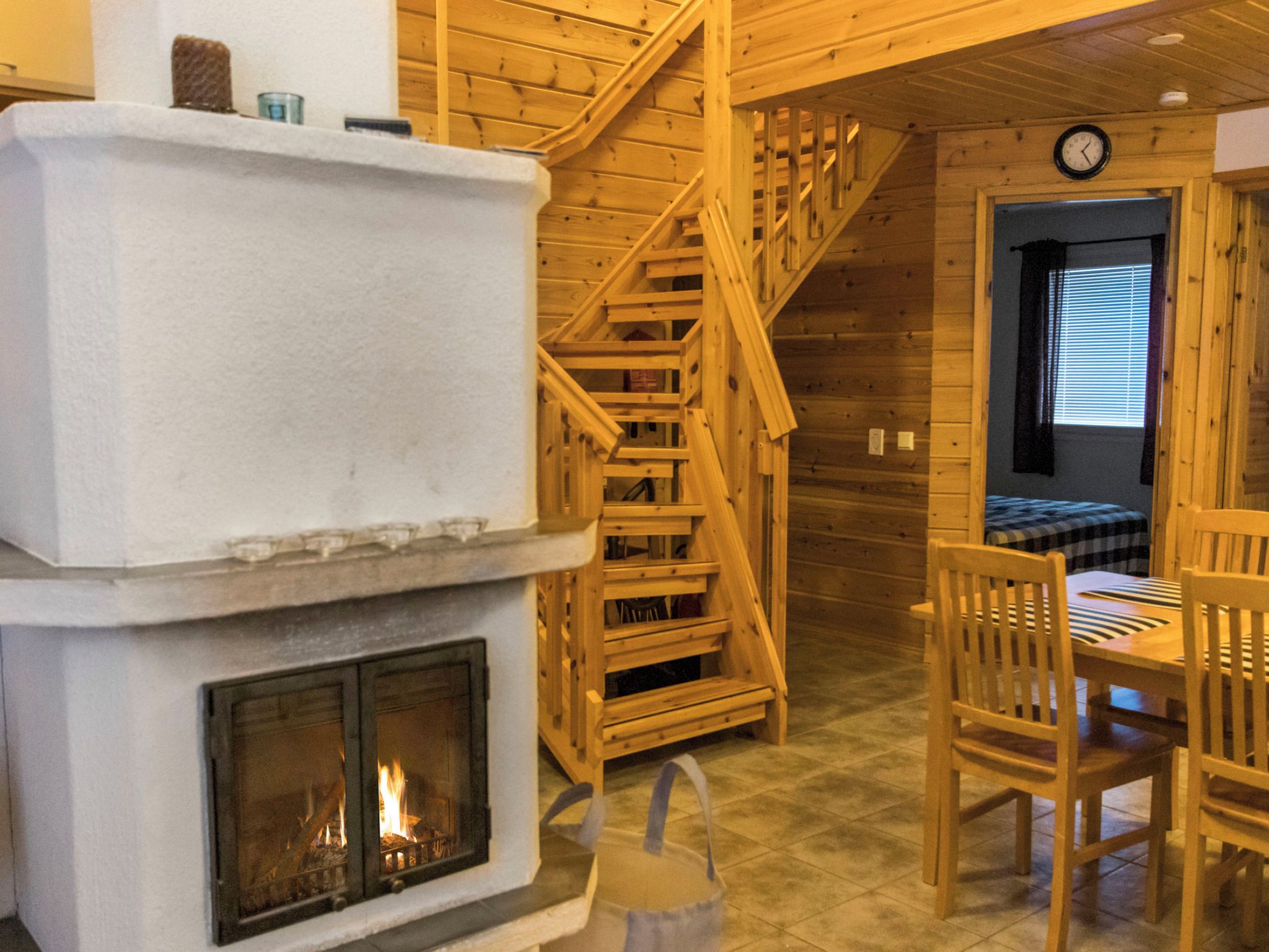 A wooden interior with a fireplace, wooden staircase, and a dining area.