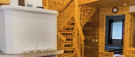 Ein Holzinnenraum mit Kamin, einer Holztreppe und einem Essbereich.