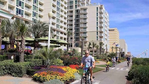 Une piste cyclable bordée d’un complexe hôtelier à plusieurs étages, doté de nombreux balcons.