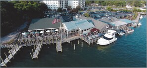 An aerial view of a waterfront restaurant with outdoor seating, a dock, and a boat.