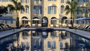 A large pool with a reflection of a building with arched windows and a tiled roof.