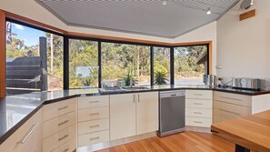 Eine moderne Küche mit einem großen Fenster, Holzschränken und einem Geschirrspüler.