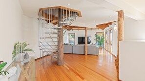 Un intérieur moderne avec un escalier en bois, un téléviseur à écran plat et un coin salon.