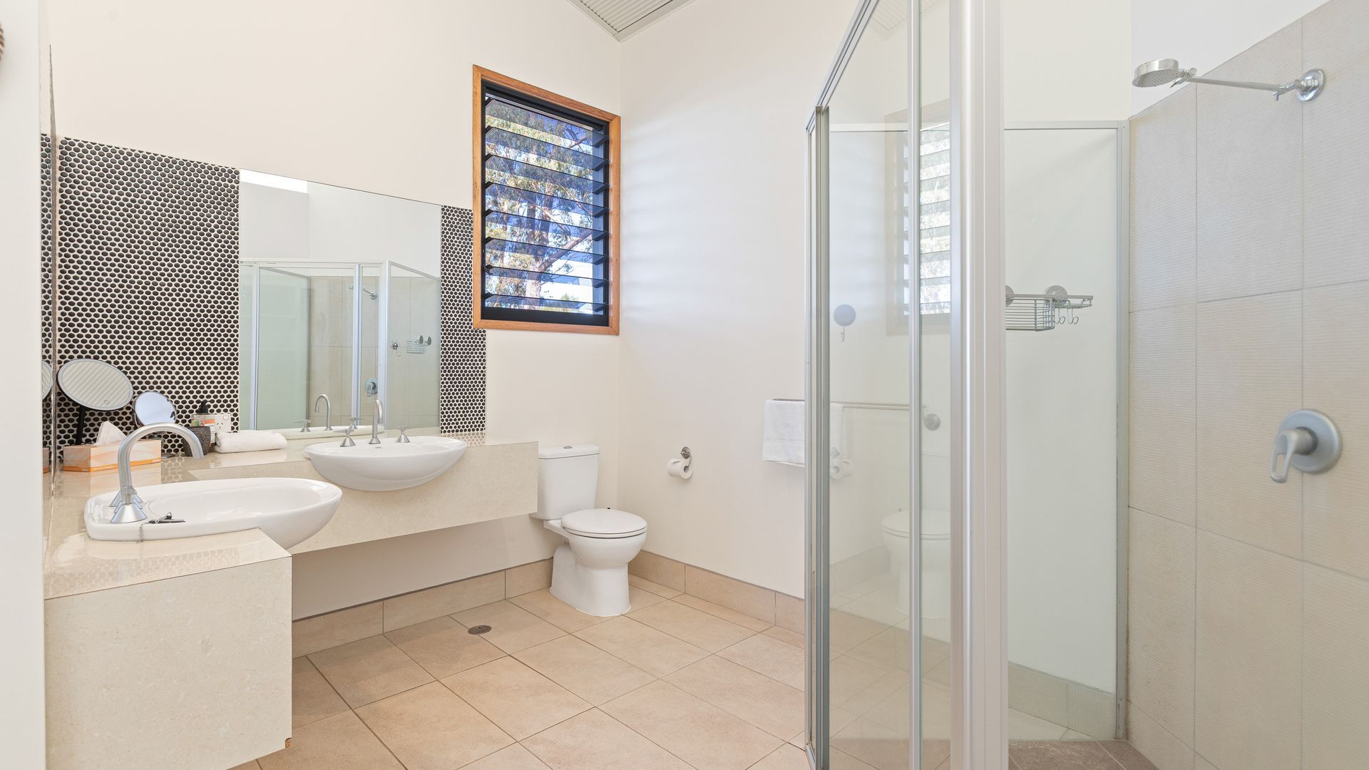 Un baño moderno con cabina de ducha de vidrio, un lavamanos con espejo y un inodoro.