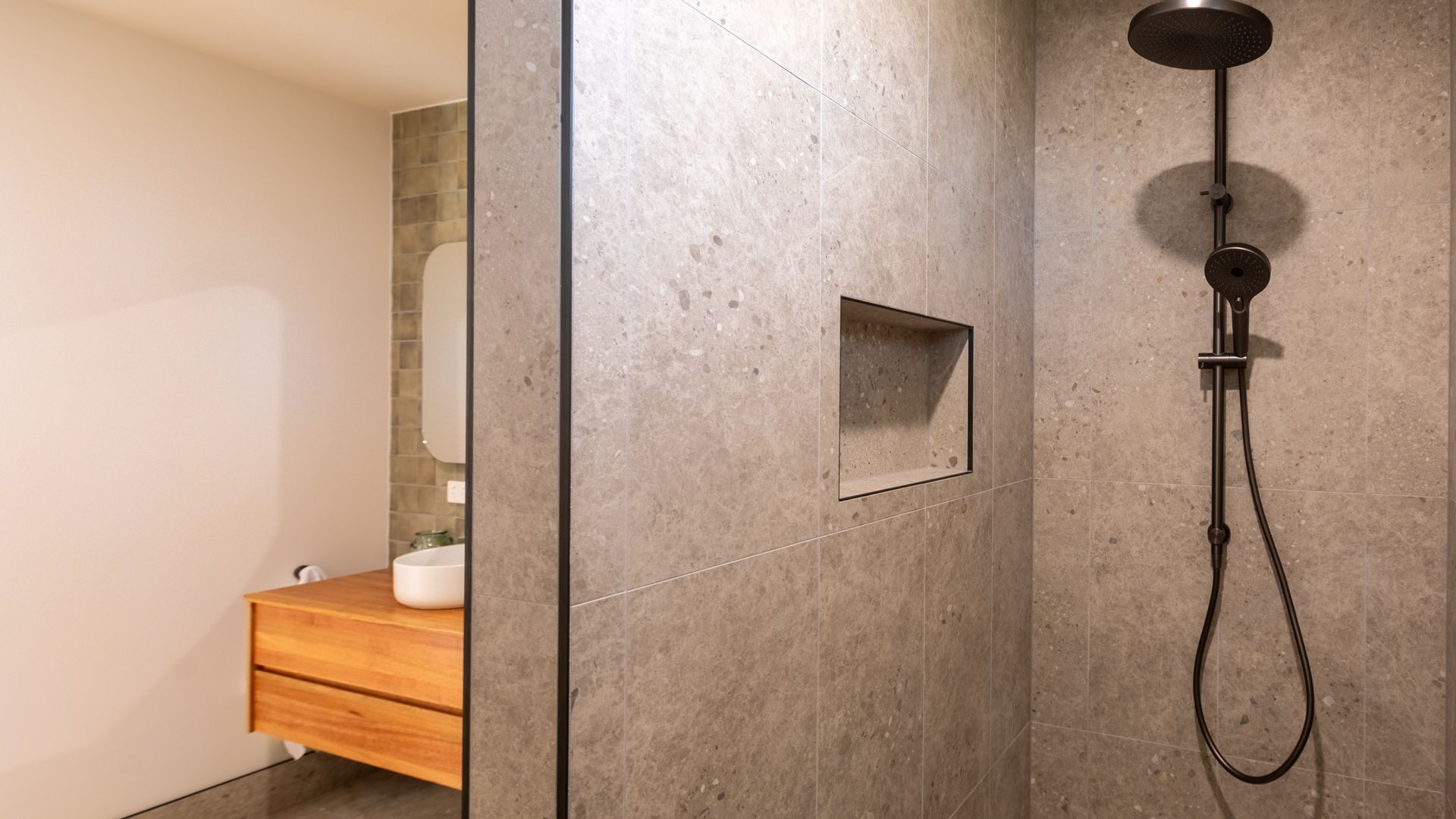 A modern bathroom with a shower, a wooden vanity, and a mirror.