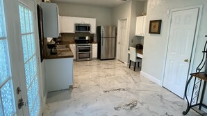 A kitchen with white cabinets, a stainless steel refrigerator, and a microwave. - Spacious 4BR 2-Story North Houston Vacation Rental (Tomball)