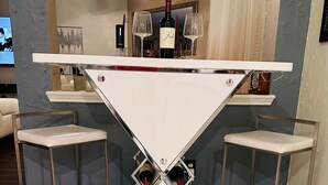 A white bar table with two stools, a wine bottle, and glasses on a marble floor. - Spacious 4BR 2-Story North Houston Vacation Rental (Tomball)