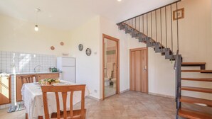 Eine Küche mit Essbereich, einer Treppe und Blick ins Badezimmer.