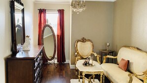 A room with a wooden floor, a large mirror, a chandelier, a sofa, and a dresser. - Spacious North Houston Getaway rental (Tomball)