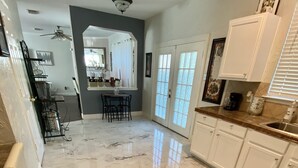 A spacious kitchen with marble flooring, white cabinets, and a dining area with a table and chairs. - Spacious North Houston Getaway rental (Tomball)