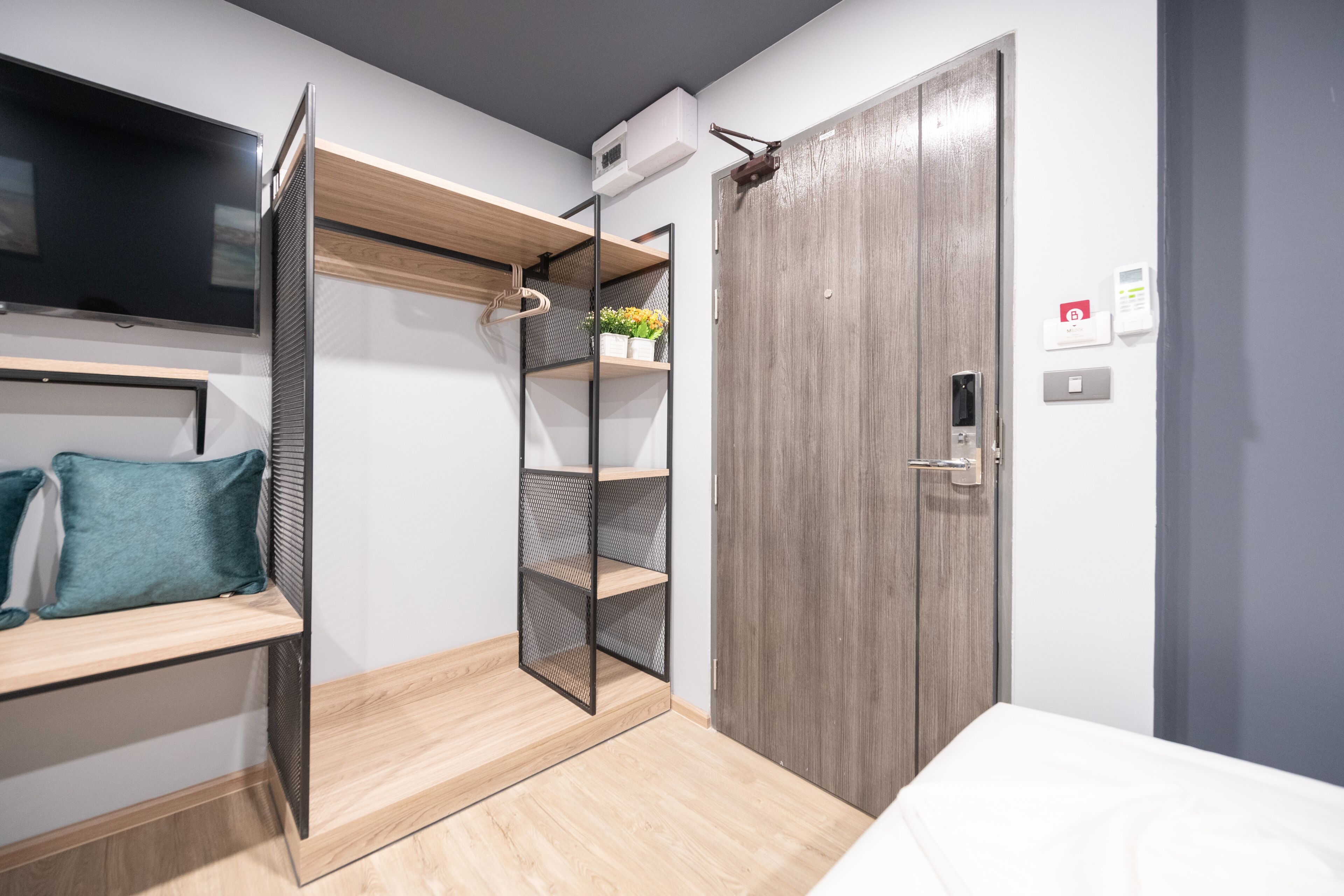 Une chambre moderne avec un lit superposé, une télévision, une armoire et une étagère.