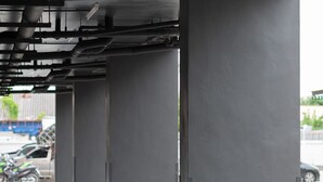 Una estructura subterránea de estacionamiento con pilares de hormigón y tuberías expuestas.