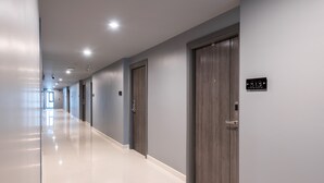 Un pasillo moderno con piso pulido, paredes grises y puertas de madera.