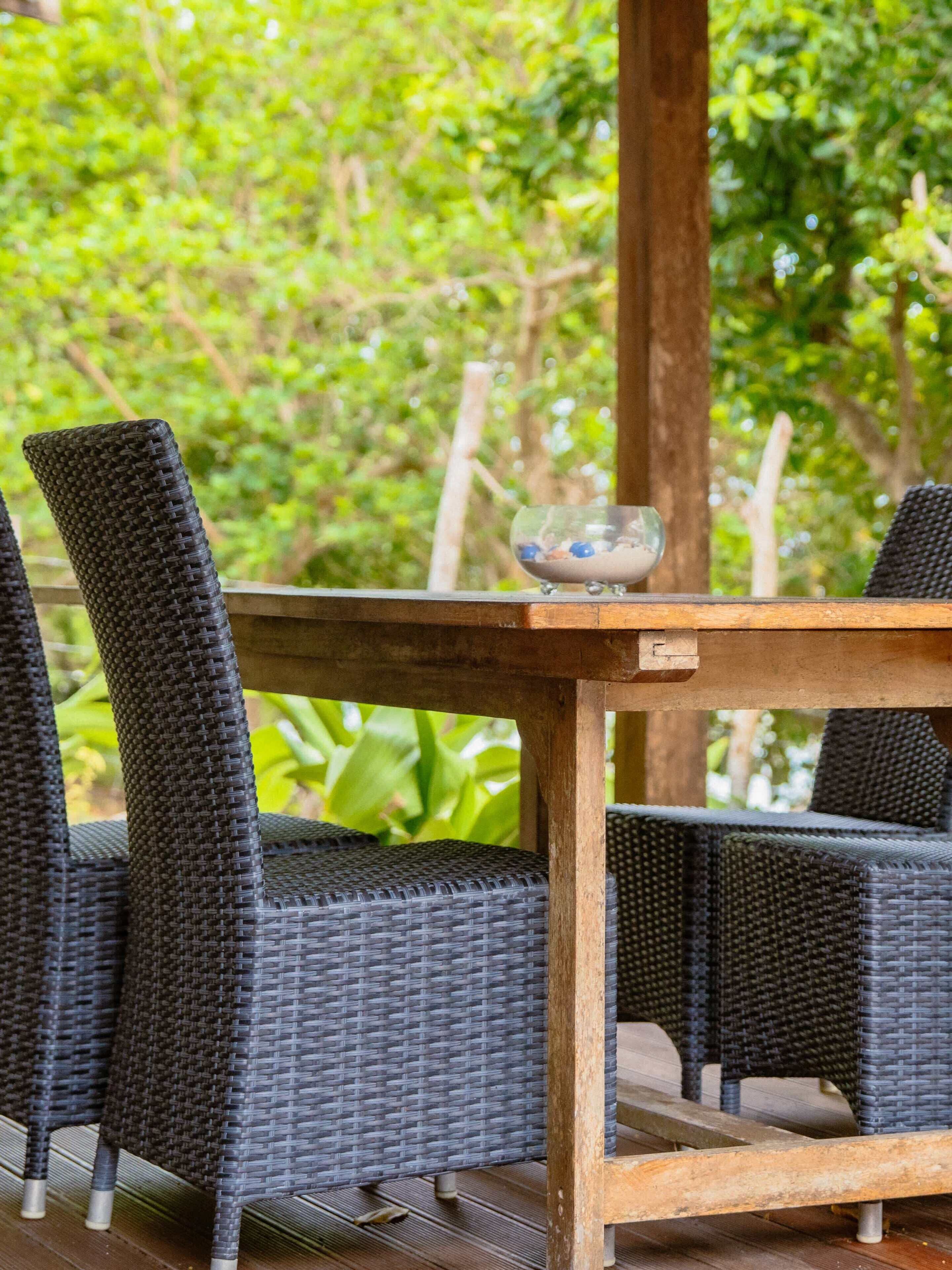 Une table en bois, un saladier en verre et deux chaises en osier.