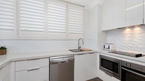 Une cuisine moderne avec des meubles blancs, un lave-vaisselle, un four à micro-ondes et un grille-pain.
