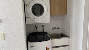A compact laundry area with a washing machine, a sink, and a compact dryer. - Oceanic Apartments Unit 13 Stunning Ocean Views (Kings Beach)