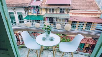 Enjoy a peaceful moment on this balcony with a small table and two chairs, surrounded by vibrant city views.