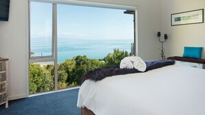 A bedroom with a large sliding glass door leading to a balcony with a view of the sea.