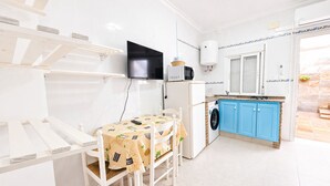 A compact kitchen with a washing machine, a microwave, and a TV. - Apartamento cerca de la playa de Conil (Conil de la Frontera)