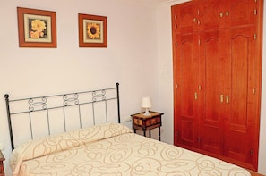 A bedroom with a bed, a nightstand, a lamp, and a wardrobe.