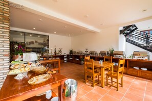 A spacious kitchen with a dining area, featuring a brick wall, a large window, and a staircase.