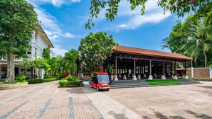 A spacious courtyard with a red car, a covered pavilion, and lush greenery. - Chez Carole Center Resort & Spa (Phu Quoc)