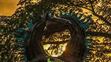 Una escultura de un caballo con el sol poniéndose al fondo.