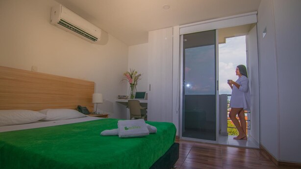 Ein Hotelzimmer mit Bett, Schreibtisch, Stuhl und Balkon.