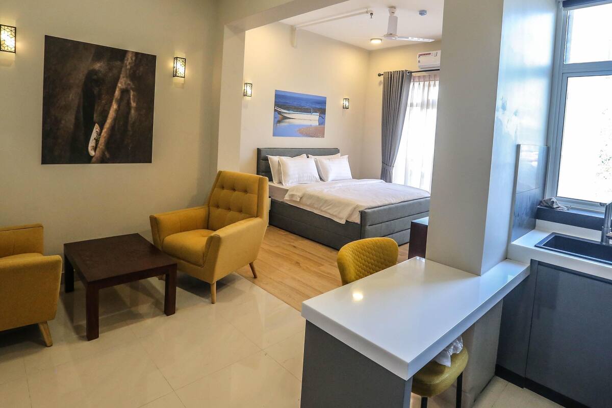 Een hotelkamer met een bed, een bureau, een stoel, een bank en een schilderij aan de muur.
