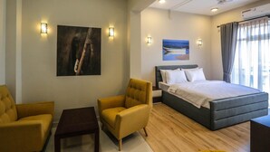 Ein Hotelzimmer mit einem Bett, zwei gelben Sesseln, einem kleinen Tisch und Bildern an den Wänden.