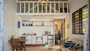 Espai habitable compacte amb zona de dinar, petita cuina i sofà amb coixins de ratlles.
