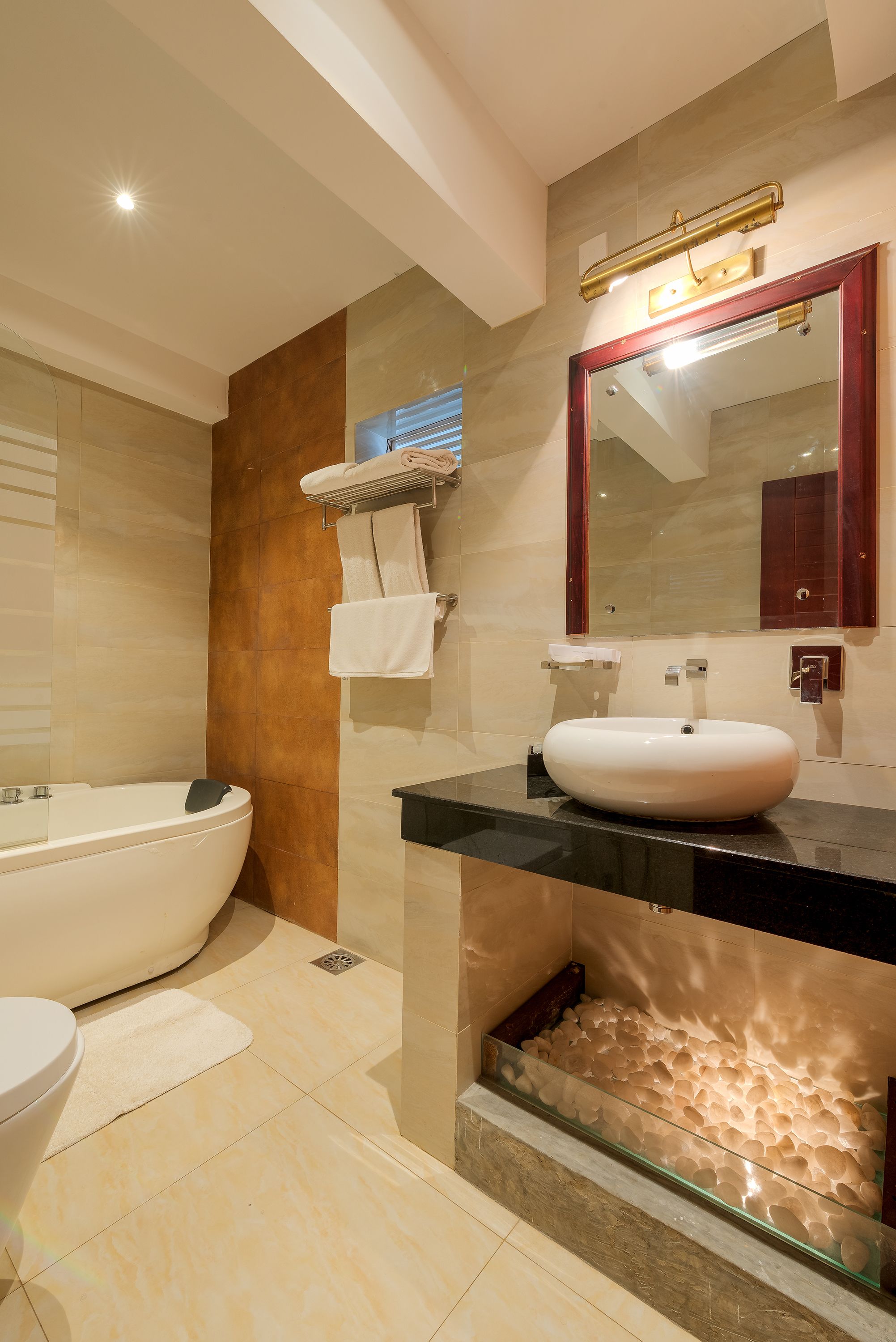 Une salle de bain moderne dotée d’une baignoire sur pieds, d’un jacuzzi entouré de parois de verre et d’un grand miroir avec un cadre en bois.