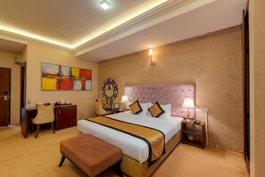 A hotel room with a large bed, a desk, a chair, a bench, and a painting on the wall. - Seagate Hotel (Kalutara)