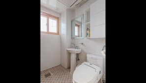 Ein Badezimmer mit Fenster, Waschbecken, Toilette und Spiegel.
