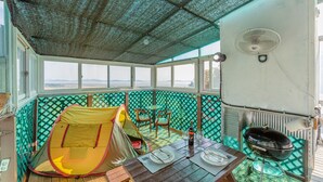 A cozy outdoor seating area with a table set for two, a tent, and a grill. - Goorm Dari Pension (Incheon)